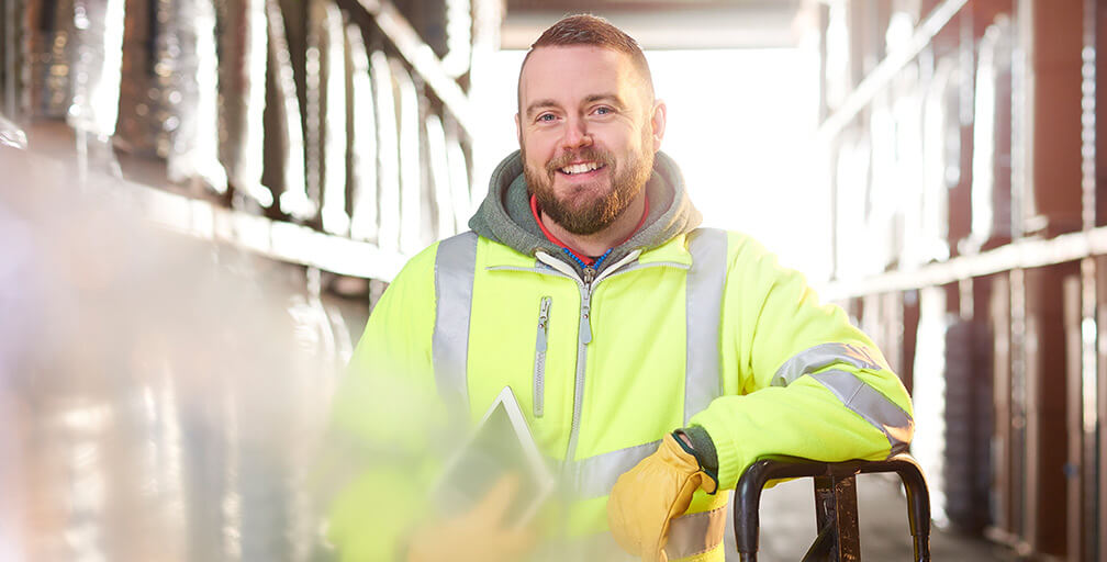 A man in a green safety vest stands in a warehouse. Learn about “How do I start my workers' comp claim in Oregon?”