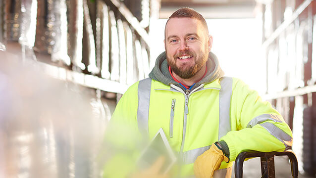 A man in a green safety vest stands in a warehouse. Learn about “How do I start my workers' comp claim in Oregon?”