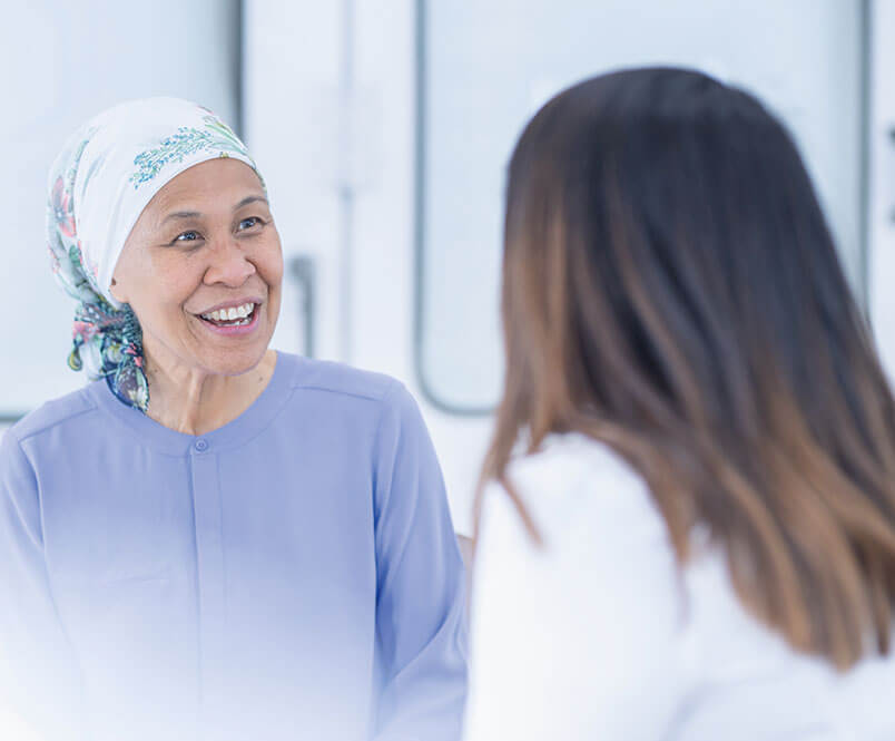 A woman smiles while talking to a doctor.